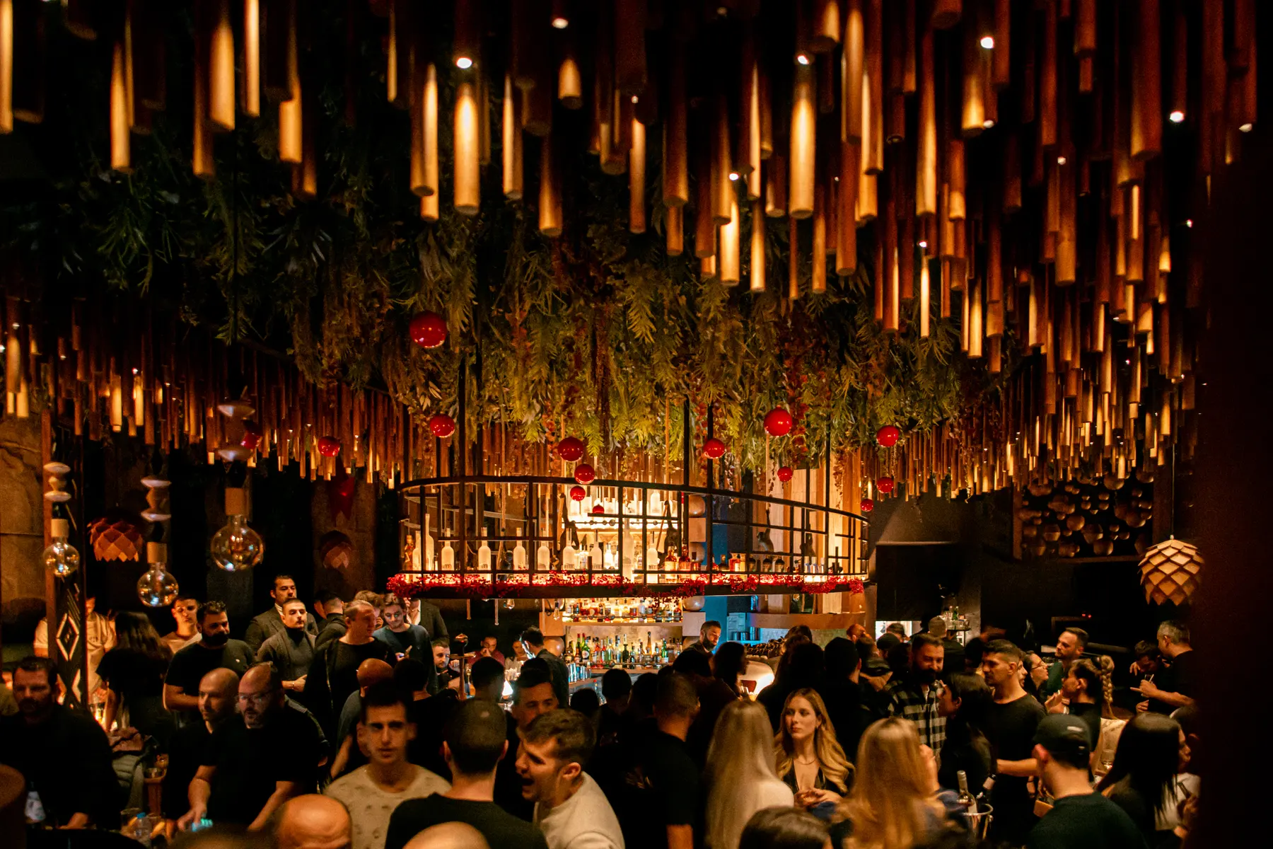 Ospiti stretti al bancone sotto le luci di bambù, a una festa privata da Iguazu Athens