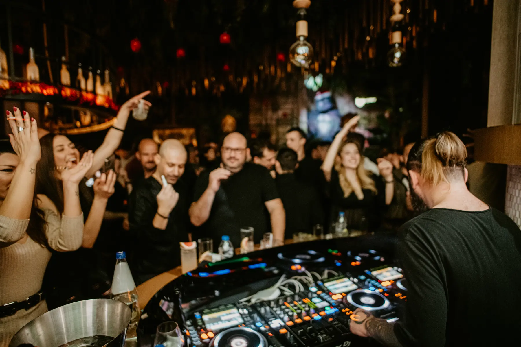 Mani in alto davanti alla postazione DJ, a una festa da Iguazu Athens
