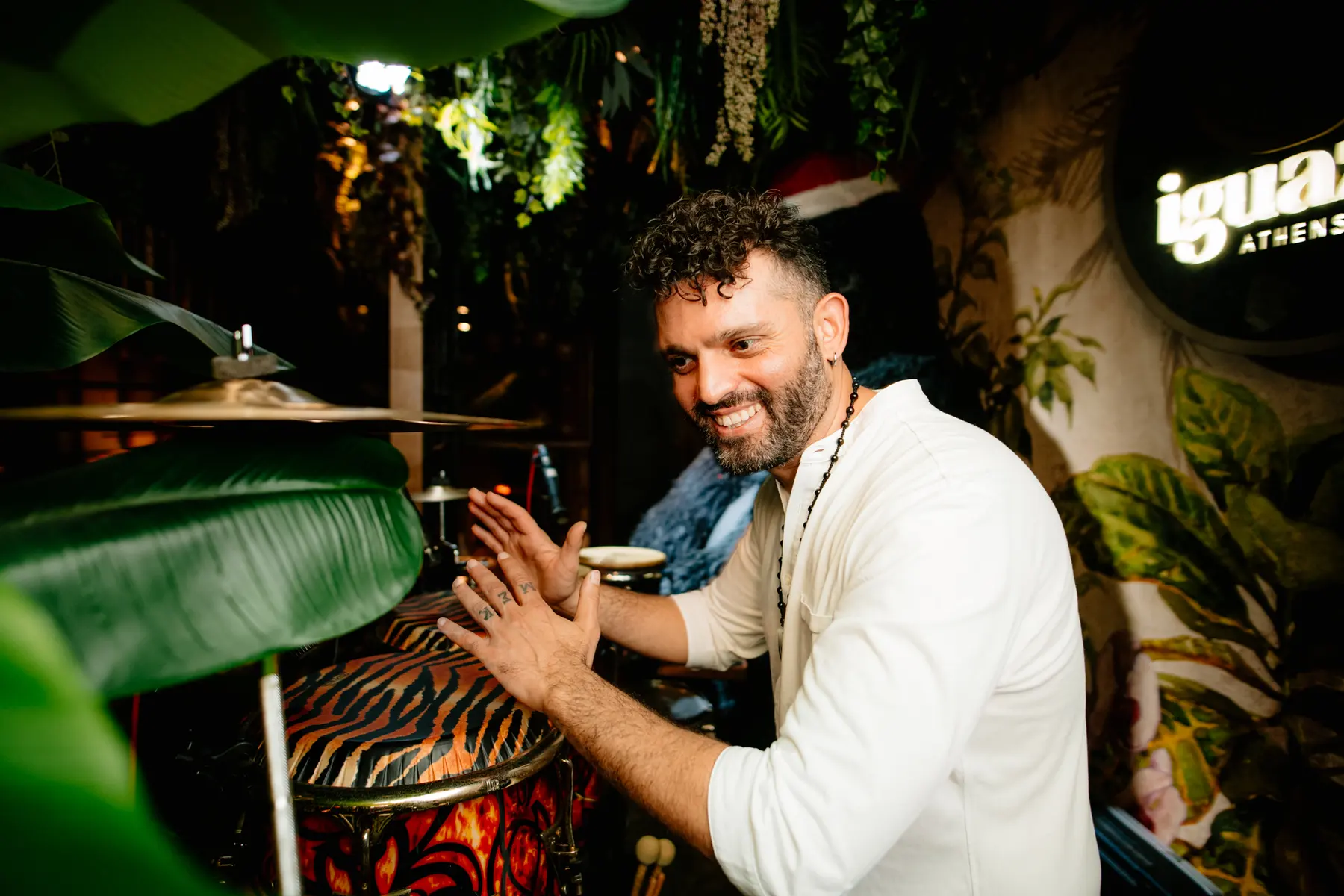 Un percussionista suona in mezzo alle piante, a una festa da Iguazu Athens