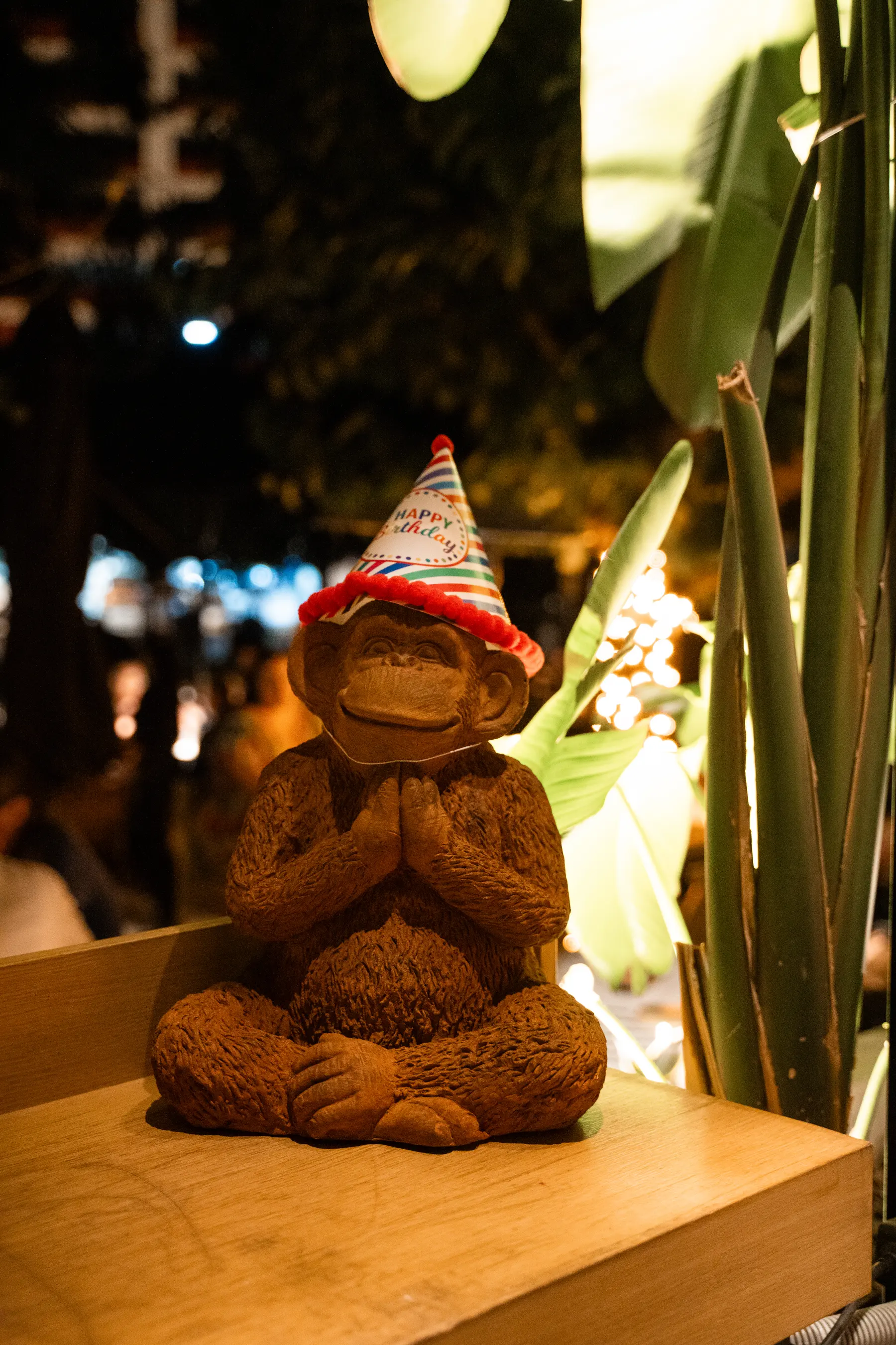 Una figura di scimmia con il cappellino da festa tra le piante da Iguazu Athens