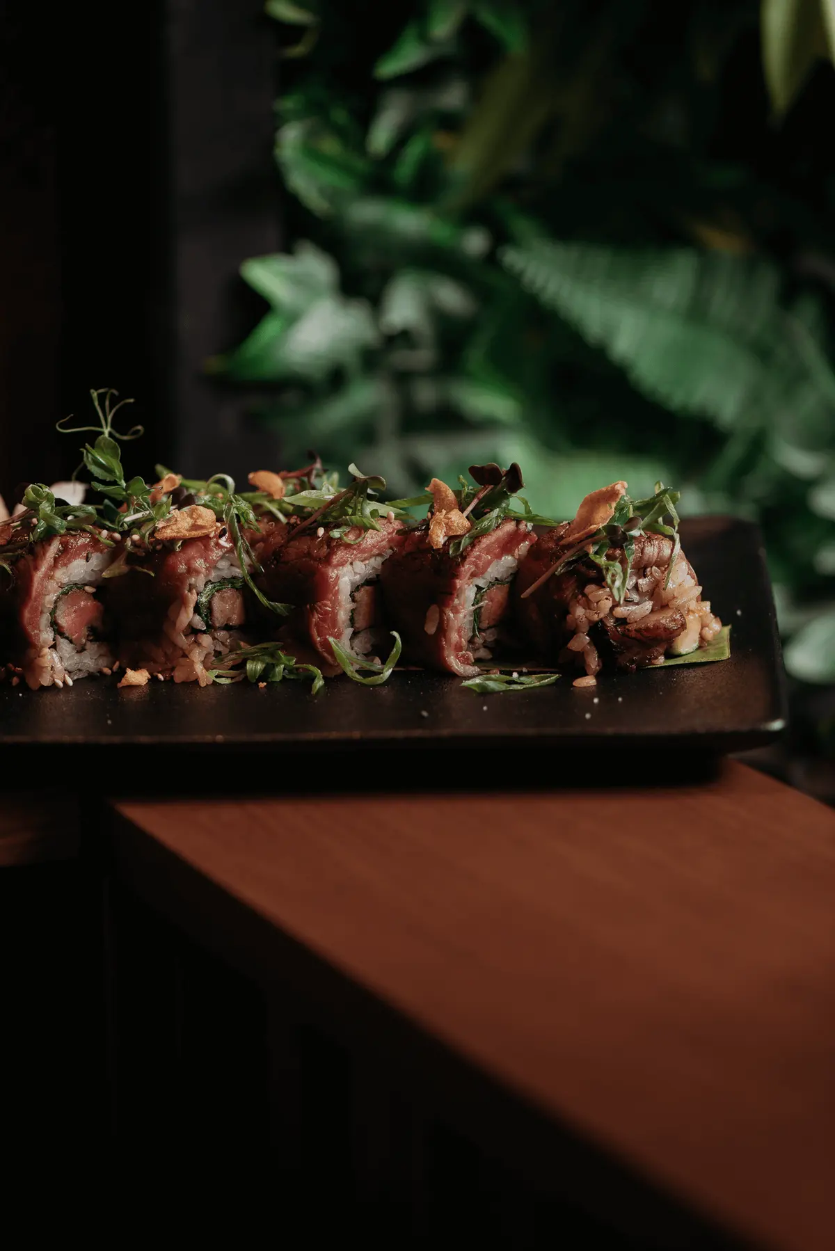 Roll di sushi con guarnizione scottata su un tagliere scuro, da Iguazu Athens